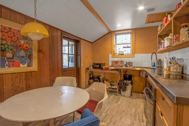 kitchen featuring stainless steel oven, hanging light fixtures, lofted ceiling, black electric cooktop, and wooden walls