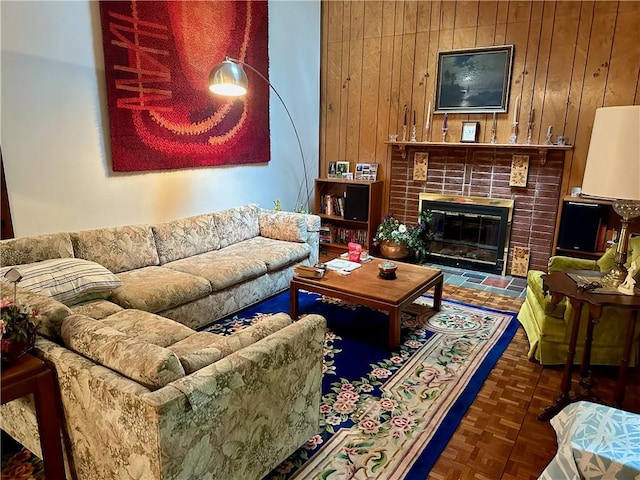 living room featuring dark parquet flooring, a fireplace, and wood walls