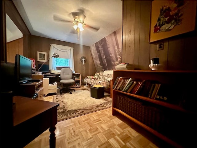 living area with light parquet flooring, ceiling fan, and wooden walls