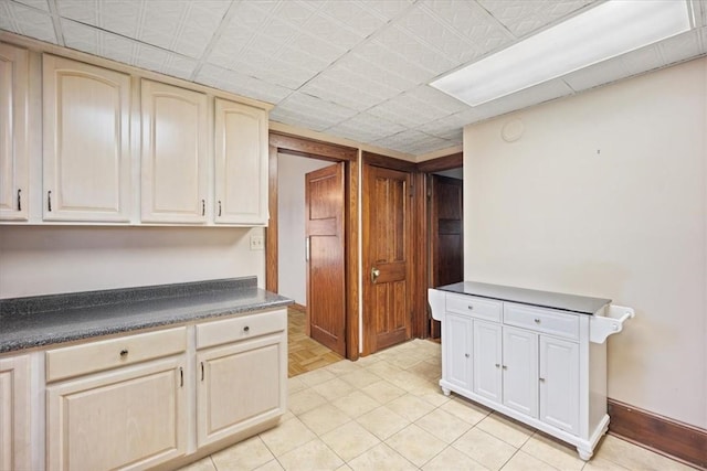 kitchen with cream cabinetry and light tile patterned flooring