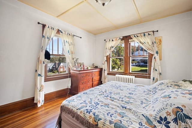 bedroom with radiator heating unit and hardwood / wood-style floors