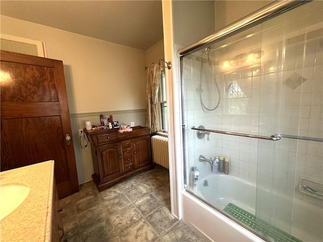 bathroom featuring radiator heating unit, vanity, and bath / shower combo with glass door