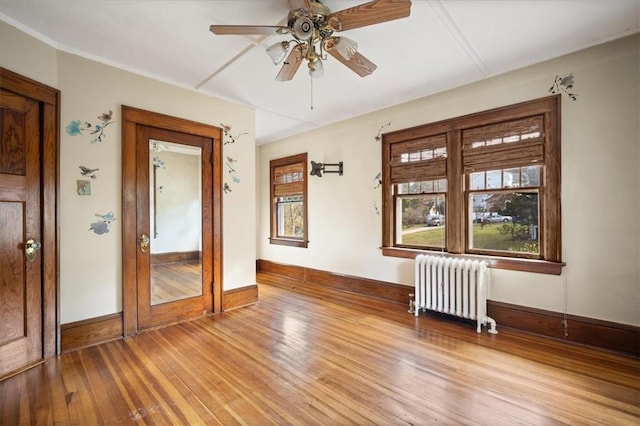 unfurnished room featuring light wood-type flooring, radiator, and ceiling fan