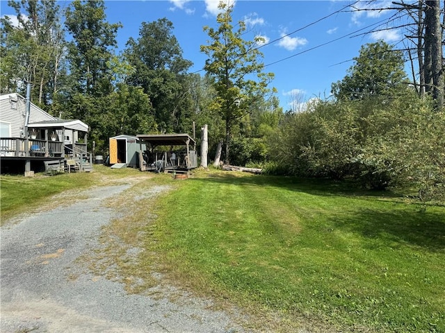 view of yard featuring a carport, a deck, and a storage unit