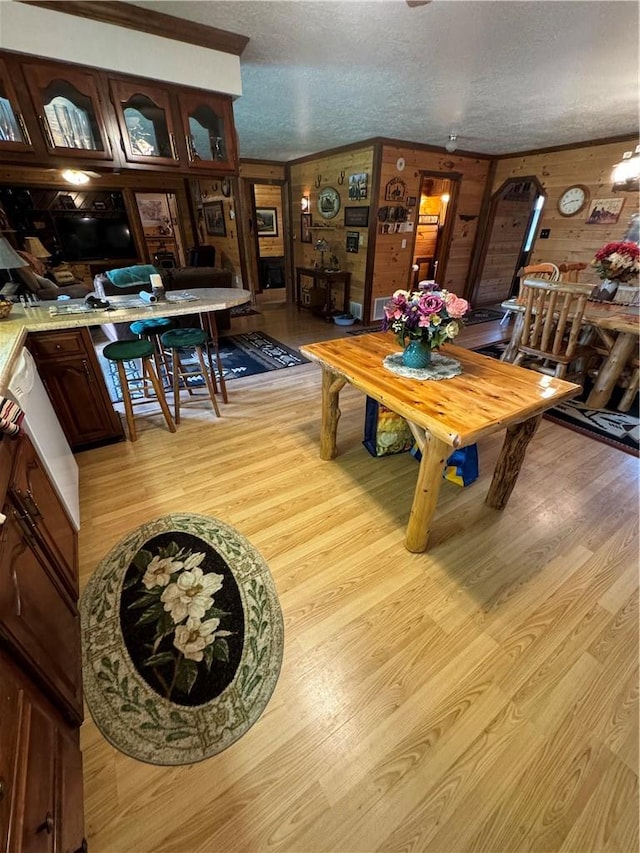 dining room featuring wood walls, a textured ceiling, and light wood-type flooring