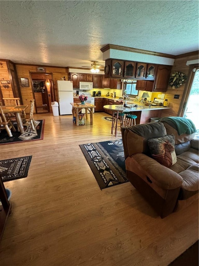 living room featuring a textured ceiling, light hardwood / wood-style floors, ceiling fan, and wooden walls