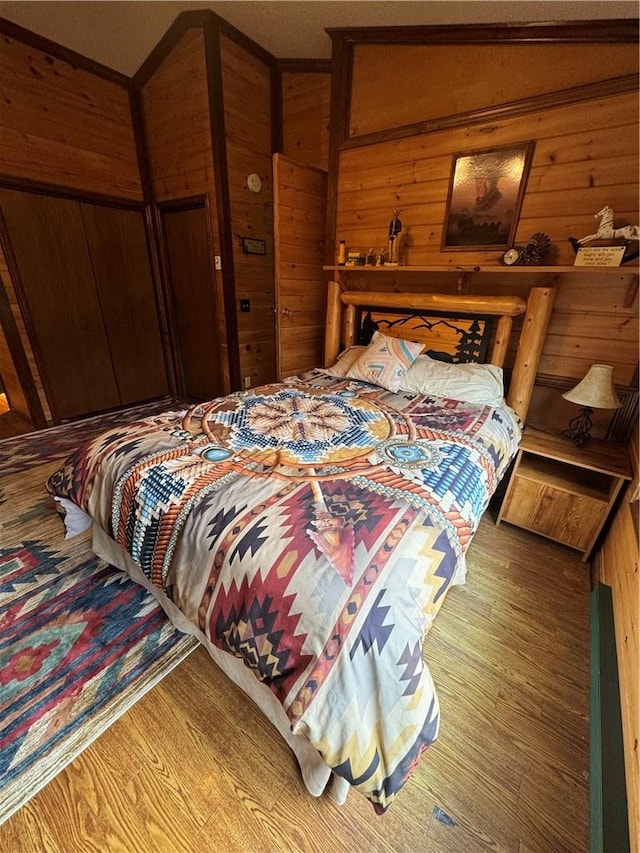 bedroom with hardwood / wood-style flooring, lofted ceiling, and wood walls