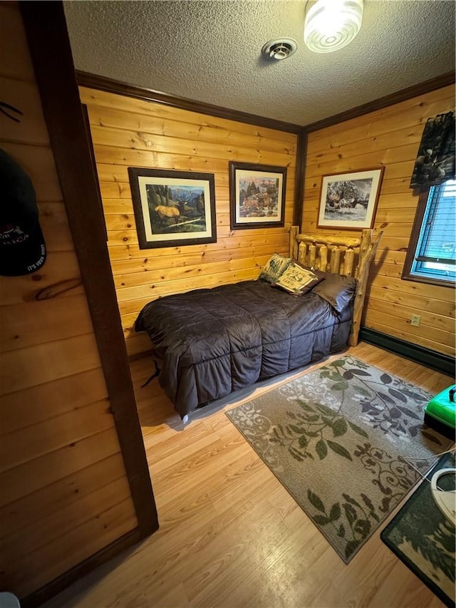 bedroom featuring wooden walls, wood-type flooring, and a textured ceiling