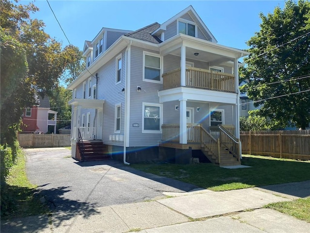 view of front of house with a balcony and a front lawn