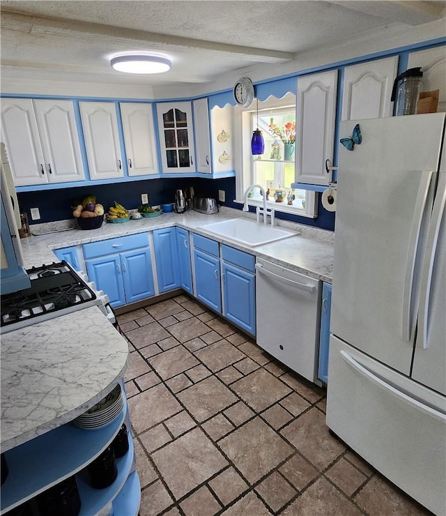 kitchen with a textured ceiling, white appliances, blue cabinets, sink, and white cabinets