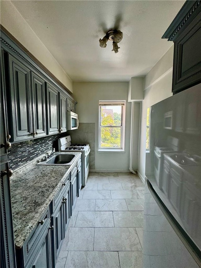 kitchen with tasteful backsplash, gas range gas stove, sink, and stone countertops