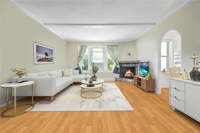 living room with beam ceiling, a fireplace, and light hardwood / wood-style flooring