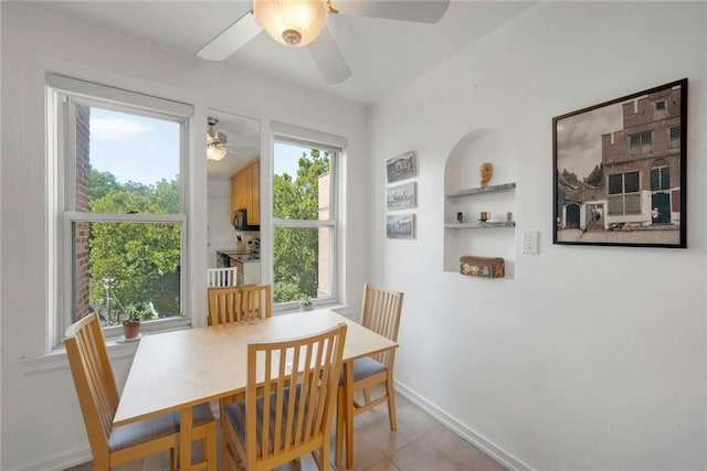 tiled dining space featuring ceiling fan, a healthy amount of sunlight, and built in shelves