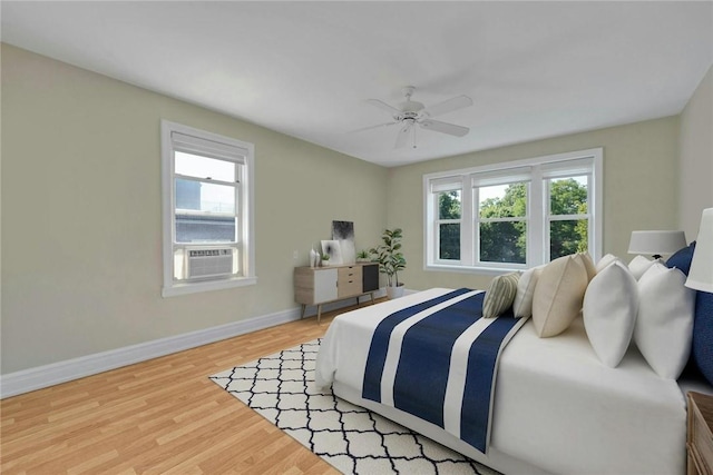 bedroom with multiple windows, ceiling fan, hardwood / wood-style floors, and cooling unit