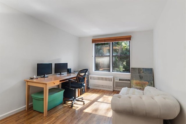 office space with a wall mounted air conditioner, hardwood / wood-style floors, and radiator heating unit