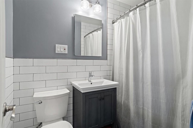 bathroom with toilet, curtained shower, tile walls, and vanity