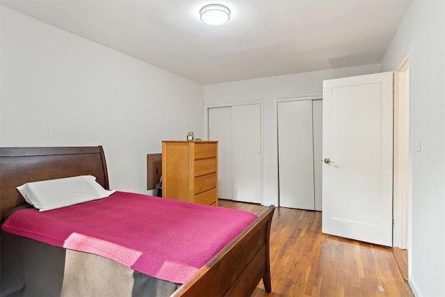 bedroom featuring multiple closets and hardwood / wood-style floors