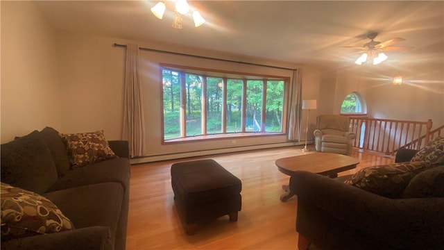 living room with light wood-type flooring, a baseboard radiator, and ceiling fan