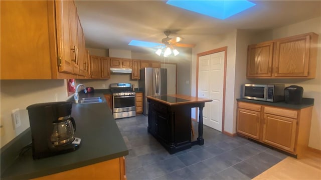 kitchen featuring a skylight, sink, a center island, and appliances with stainless steel finishes