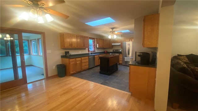 kitchen featuring a skylight, sink, stainless steel appliances, dark hardwood / wood-style flooring, and a kitchen island