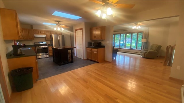 kitchen with a center island, a skylight, baseboard heating, appliances with stainless steel finishes, and wood-type flooring