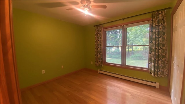 empty room featuring ceiling fan, light hardwood / wood-style flooring, and a baseboard heating unit