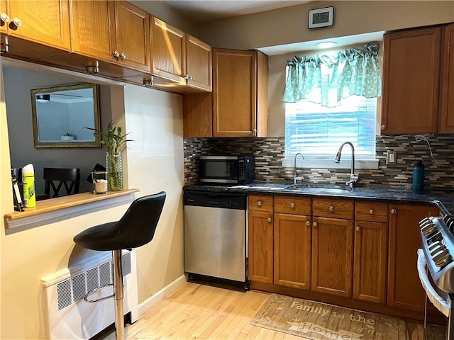 kitchen featuring decorative backsplash, stainless steel appliances, light hardwood / wood-style flooring, and sink