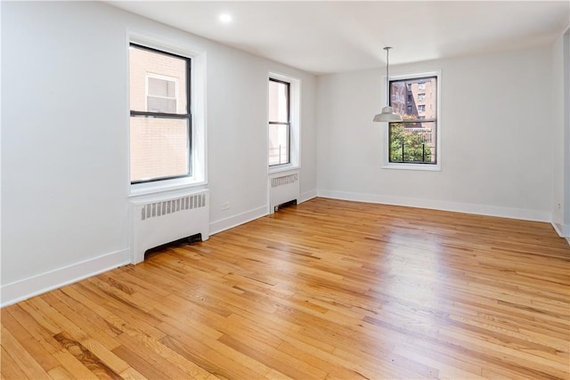unfurnished room featuring light hardwood / wood-style floors and radiator heating unit
