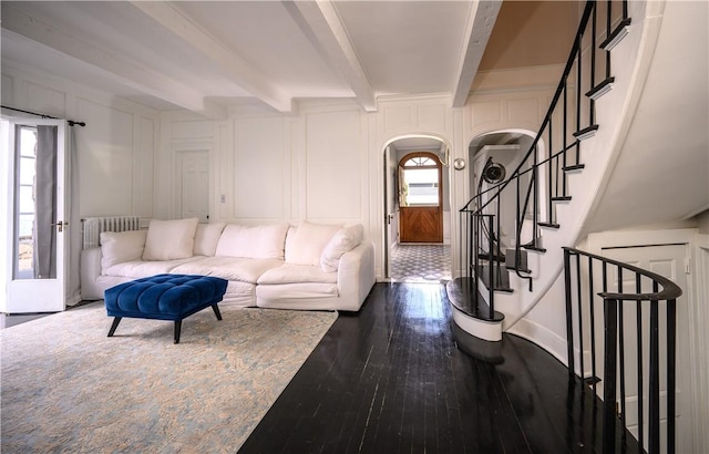 living room featuring beam ceiling, radiator heating unit, dark wood-type flooring, and a healthy amount of sunlight