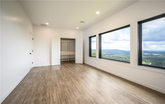 unfurnished bedroom with a mountain view, hardwood / wood-style flooring, and a closet