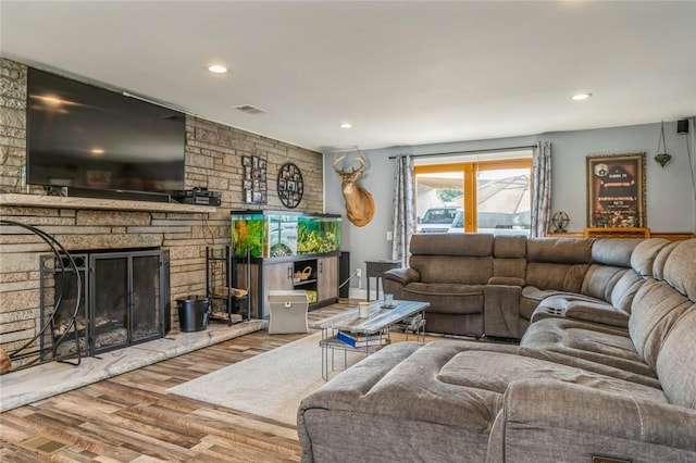 living room featuring a stone fireplace and wood-type flooring