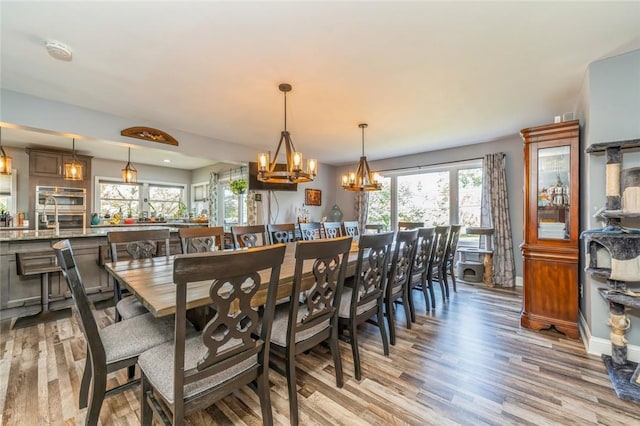 dining area with plenty of natural light, an inviting chandelier, and light hardwood / wood-style flooring