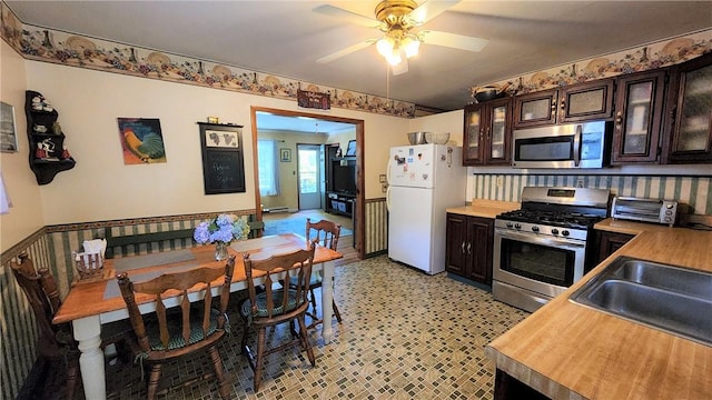 kitchen featuring dark brown cabinets, stainless steel appliances, ceiling fan, sink, and butcher block countertops