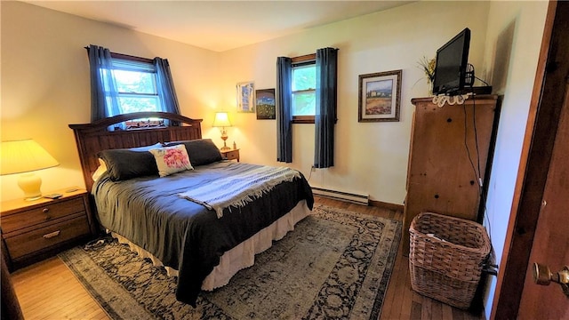 bedroom with light hardwood / wood-style flooring and a baseboard heating unit