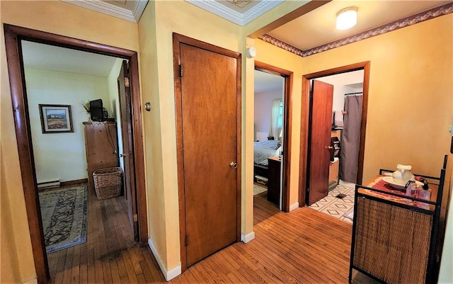 hallway featuring light hardwood / wood-style floors, ornamental molding, and a baseboard radiator