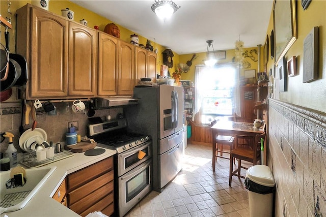 kitchen with double oven range, ventilation hood, sink, hanging light fixtures, and tasteful backsplash