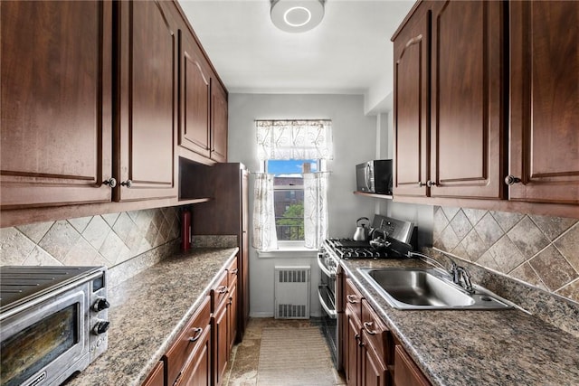 kitchen with decorative backsplash, radiator heating unit, stainless steel range with gas cooktop, and sink