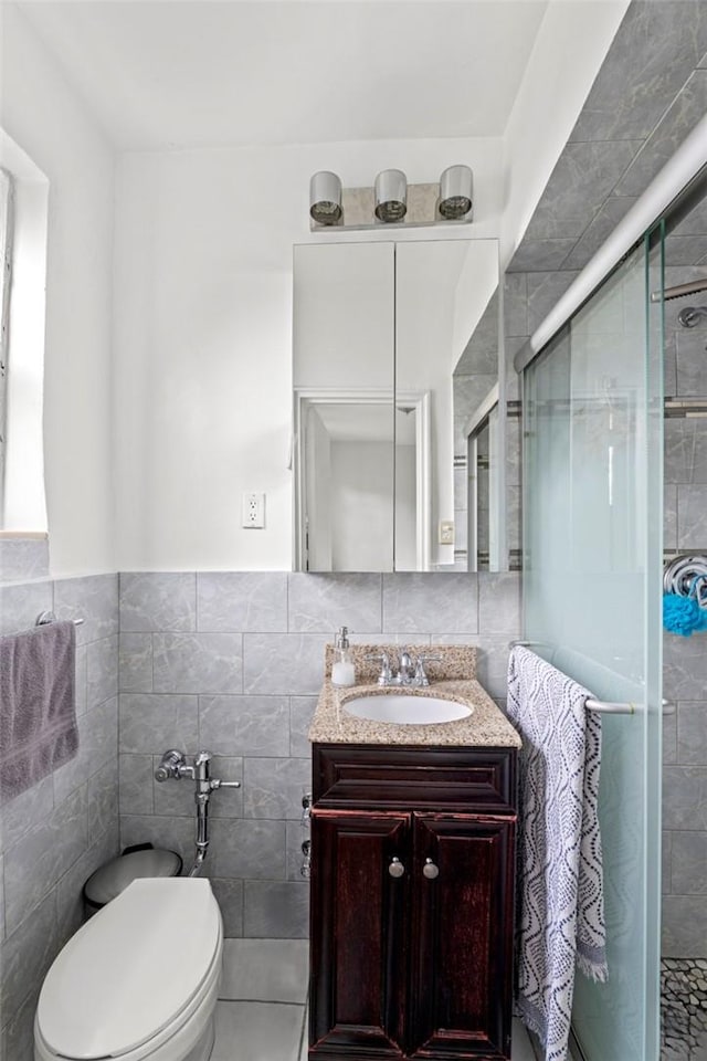 bathroom with vanity, an enclosed shower, and tile walls