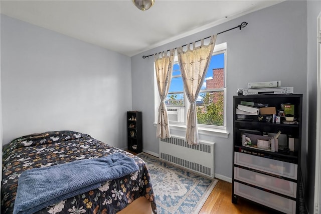 bedroom featuring radiator heating unit and wood-type flooring