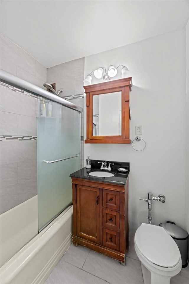 full bathroom featuring tile patterned floors, vanity, toilet, and bath / shower combo with glass door