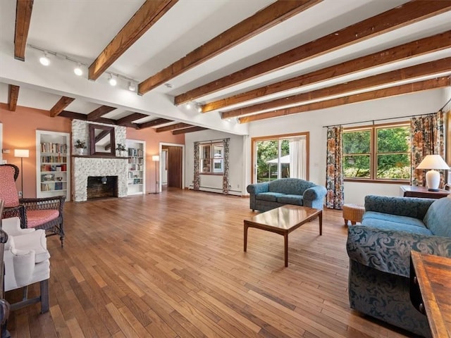 living room with beam ceiling, a baseboard radiator, light hardwood / wood-style floors, track lighting, and a fireplace