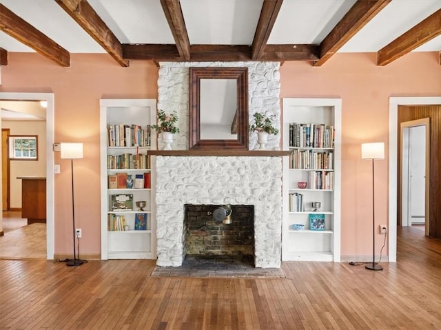 unfurnished living room with beam ceiling, hardwood / wood-style flooring, a stone fireplace, and a baseboard heating unit