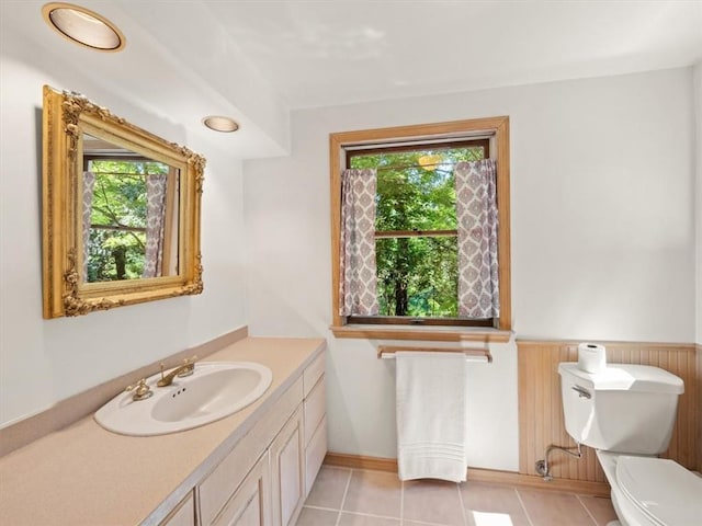 bathroom featuring tile patterned flooring, vanity, toilet, and wooden walls