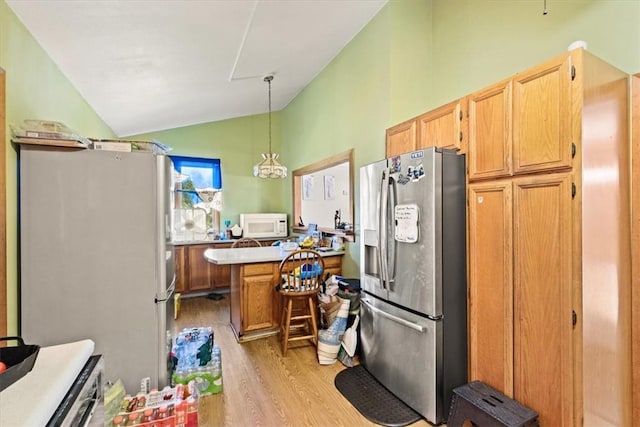 kitchen with vaulted ceiling, hanging light fixtures, white appliances, and light wood-type flooring