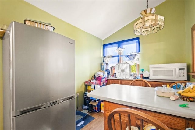 kitchen with stainless steel fridge, light hardwood / wood-style floors, and vaulted ceiling