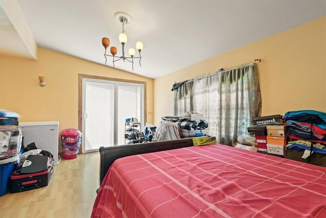 bedroom with hardwood / wood-style floors, vaulted ceiling, and an inviting chandelier