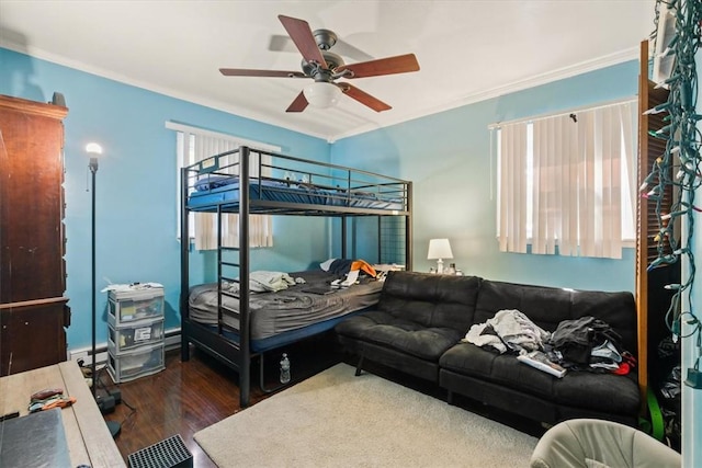 bedroom featuring ceiling fan, dark hardwood / wood-style flooring, crown molding, and a baseboard heating unit