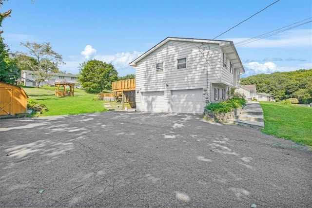 view of home's exterior featuring a garage, a lawn, and a wooden deck