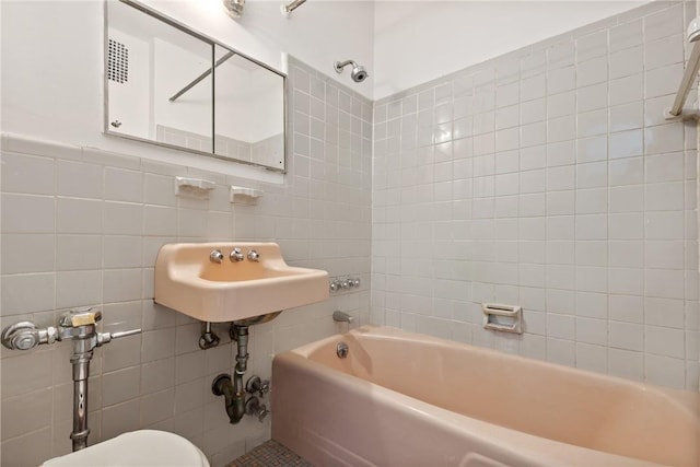 full bathroom with sink, toilet, tile walls, and tiled shower / bath