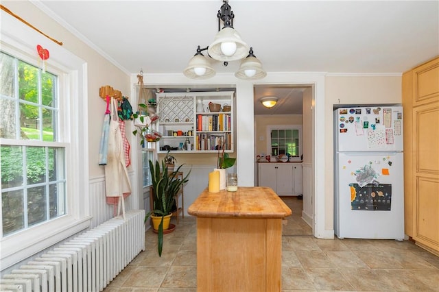 kitchen with wood counters, light brown cabinetry, pendant lighting, radiator heating unit, and white fridge